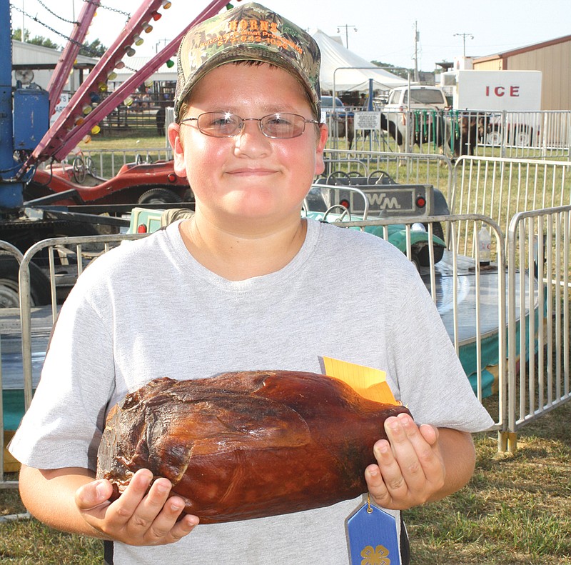 Lane Huntsman holds his first cured ham. He earned a blue ribbon for it during the country ham show Tuesday at the Kingdom of Callaway County Fair.