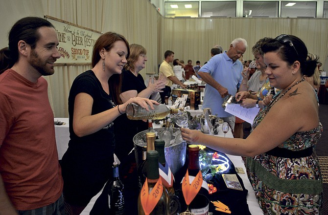 Thomas Adams and Leah Wood of Serenity Valley Winery serve up a sample of their sweet white to Osage Beach resident Lindsey Simon at the festival Saturday in Lake Ozark, Mo.