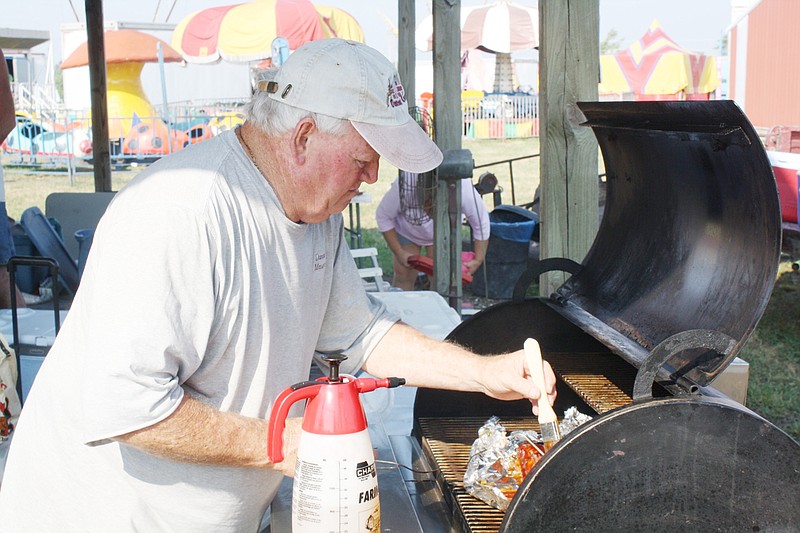 Bob Duncan of Fulton, brushes sauce onto his ribs. Duncan said he has competed at the county fair's barbecue challenge a number of times over the years.