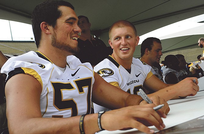 
Missouri teammates Brad Madison (57) and Jimmy Costello share a laugh while signing autographs Sunday during Fan Day at Faurot Field. 