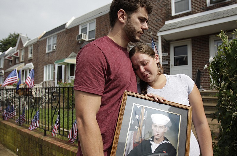 Charles Strange III, left, and his sister, Katelyn, hold a photo of their brother, Petty Officer First Class Michael Strange, outside his family's home Sunday in northeast Philadelphia. Strange was one of the Navy SEALs killed in a helicopter crash Friday in eastern Afghanistan.