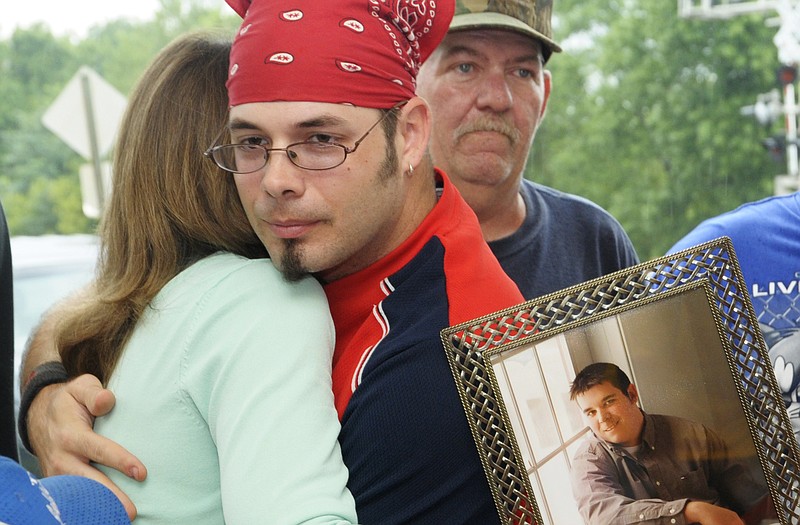 While holding a portrait of her son, Craig Tuttle, Sherry Koetting receives a hug from Corey Johnson, a co-worker of Tuttle's at Capitol Projects West. Tuttle recently passed away and to honor him, the family used memorial contributions to build a pavilion for the employees. 