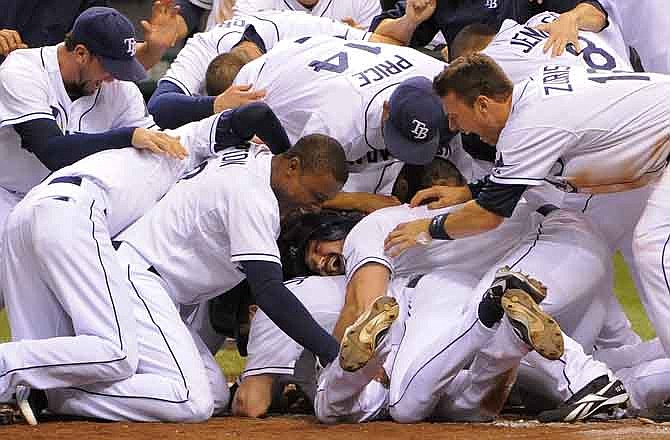 Tampa Bay Rays Sam Fuld, bottom center, is piled on by teammates after hitting a triple, scoring Elliot Johnson and scoring himself on a throwing error by Kansas City Royals second baseman Johnny Giavotella to end the ninth inning of a baseball game Wednesday, Aug. 10, 2011, in St. Petersburg, Fla. The Rays won 8-7.