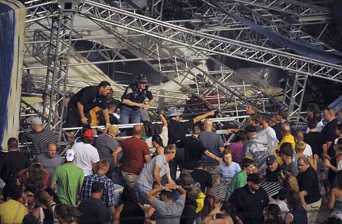 Fans waiting to see Sugarland attempt to hold up the stage after high winds blew the stage over at the Indiana State Fair Grandstands, Saturday, Aug. 13, 2011, in Indianapolis. About a dozen people are reported to have injuries after the stage collapsed. (AP Photo/The Indianapolis Star, Matt Kryger)