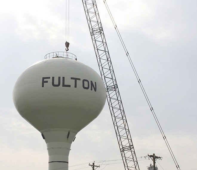 Workmen from an Indiana specialty tank contractor attach a cable Friday to the top of the unused water tower on the south side of Fulton next to Keen Ford Inc. On Monday workmen plan to split the 500,000-gallon tower in half, insert a stand pipe, reassemble the single-pedestal tower and raise it to 48.5 feet. The extra height will be as high as two other towers in the city and allow the south tower to be returned to service with more reliable water pressure in the area around the tower.