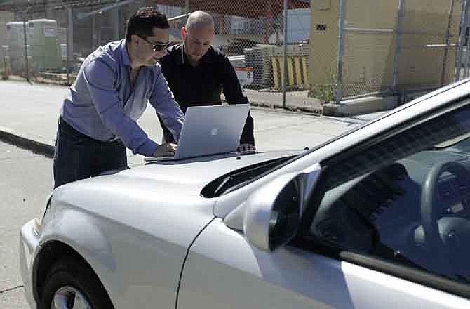 In this photo taken Tuesday, Aug. 16, 2011, security consultants Don Bailey, left, and Mathew Solnik, right, with iSEC Partners, demonstrate with a computer how they force cars with certain alarm systems to unlock their doors and start their engines by sending them text messages in San Francisco. 