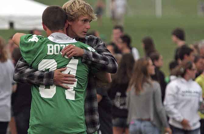 A mourner wearing the #34 Mainland Football jersey of Edgar Bozzi hugs a Mainland Regional High School student during a memorial vigil for four members of the school's football team, including Bozzi, who were killed Saturday in a crash on the Garden State Parkway, Sunday, Aug. 21, 2011 in Linwood, N.J.