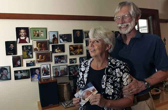 Eileen and Doug Flockhart laugh as she holds a picture of their seventh grandchild near a wall full of family photos in their home in Exeter, N.H., Wednesday, Aug. 24, 2011. America is swiftly becoming a granny state. Less frail and more engaged, today's grandparents are shunning retirement homes and stepping in more than ever to raise grandchildren while young adults struggle in the poor economy. 