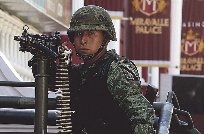 A soldier holds a machine gun outside a casino in Monterrey, Mexico, Saturday, Aug. 27, 2011. According to an official of Mexico's Attorney General's Office,  soldiers and federal agents have confiscated hundreds of slot machines at five casinos in Monterrey. A surveillance tape showed eight or nine men arriving in four cars Thursday at the Casino Royale in Monterrey and setting fire to the building, trapping dozens of people inside and killing at least 52 people. (AP Photo/Arnulfo Franco)