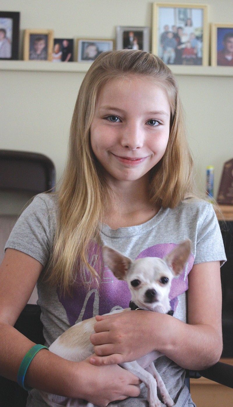 Sydney Nelson, 10, of Fulton, holds her teacup chihuahua, Priscilla, on Wednesday at her great-grandma's home in Fulton. Nelson was injured in an ATV accident on July 14. There will be a benefit for her from noon to 5 p.m. Sunday, Sept. 18, at the Fulton VFW.