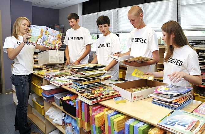 Clockwise from left, Randi Abbott, James Bernskoetter, Trevor Dusheke, Kyle Maddox and Grace Cook, all students from the leadership class at Calvary Lutheran High School, spent most of Thursday morning at the Southwest Early Childhood Education building helping to sort and put away children's books.