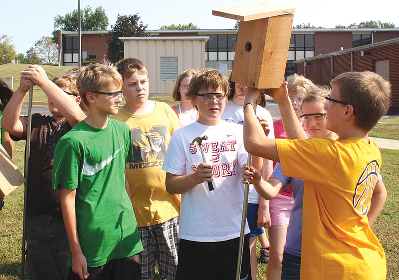 Kaden Helsel, 12, sets his group's bluebird house on its post Thursday at South Callaway Middle School as his sixth-grade classmates assist.