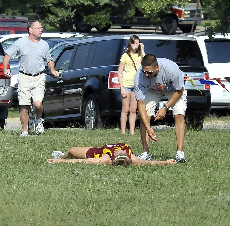 Spectators tend to a cross country runner who collapsed on the course Saturday at the Jim Marshall Cross Country Invitational. Eleven female athletes had to be treated at the scene.