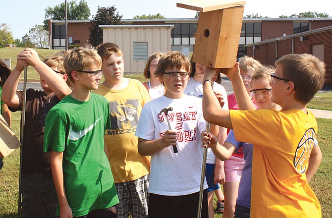 Kaden Helsel, 12, sets his group's bluebird house on its post last week at South Callaway Middle School as his sixth-grade classmates assist.