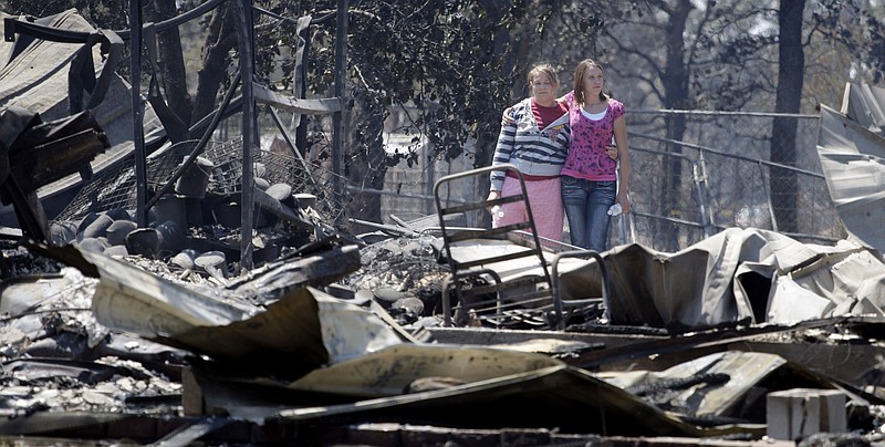 Sisters Laura, left, and Michelle Clements survey their fire-destroyed home Tuesday in Bastrop, Texas. The Clements lost their home to fires Monday.