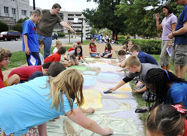 Cedar Hill art teacher Rick Rother, left, directs the work of his art club students Friday on the sidewalk along West High Street. The chalk art was patriotic in remembrance of Sept. 11 in the Chalk Art Fest, part of the Connect to the Arts Festival. In the background, students from West Elementary works on their chalk art.
