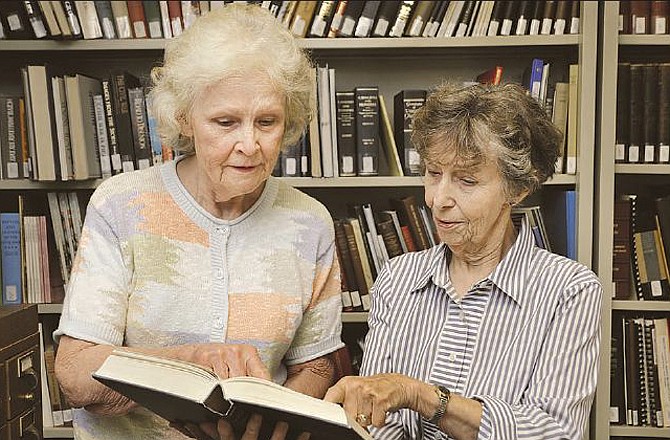 Anne Gue, left, and Marilyn Gross look over one of the many books donated by Gross to the Cole County Historical Society. 