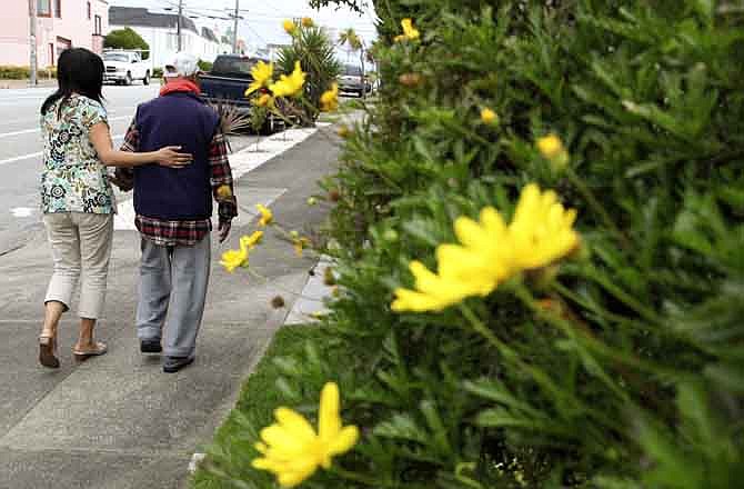 Shirley Rexrode, left, assists her father, Hsien-Wen Li, who is an Alzheimer's patient, with his daily walk, in San Francisco, in this photo taken Thursday, Sept, 1, 2011. Dementia is poised to become a defining disease of a rapidly aging population - and a budget-busting one for Medicare, Medicaid and families. The Obama administration is developing the first national Alzheimer's plan to combine research aimed at fighting dementia with help for caregivers.