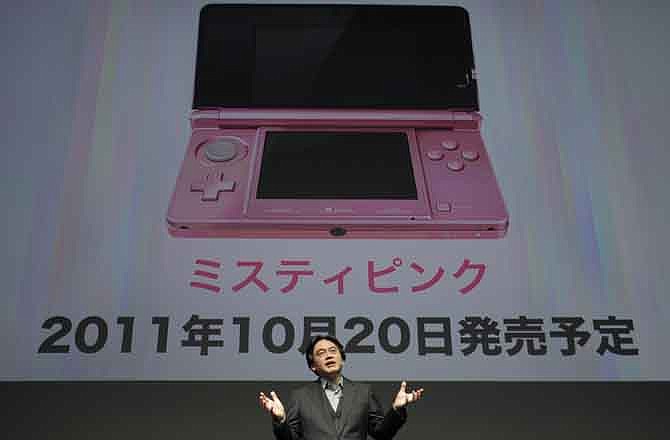 Nintendo President Satoru Iwata, standing in front of an image of a pink-color model of the 3DS portable to woo women users, speaks during a news conference at a convention center in Tokyo, Japan, Tuesday, Sept. 13, 2011. Nintendo is readying an array of video games for the holidays in an aggressive attempt at catch-up for lost time from the sales delay of the 3DS portable machine last year.