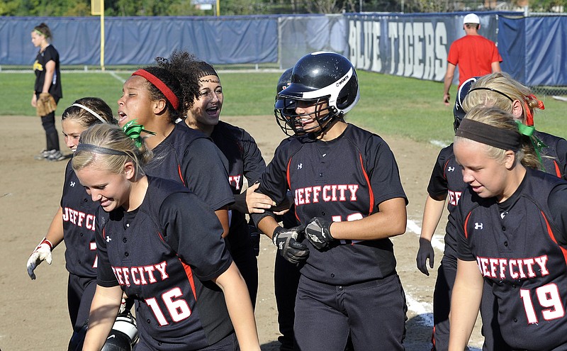 Jordan Moore (center, wearing helmet) walks back toward the dugout with her Jefferson City teammates after hitting a grand slam in the fourth inning of Monday's game against the Sedalia Smith-Cotton Lady Tigers at Lincoln Field.