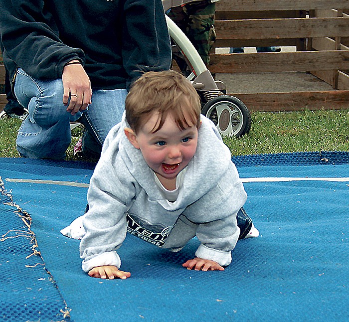 Zoey Borts, 12 months, daughter of Anthony and Jesse Borts, Jamestown, can hardly contain her excitement as she crawls to the finish line at the Diaper Derby Saturday morning on the post office lawn at the Ham & Turkey Festival. Zoey was the first place winner in the girls division. The Diaper Derby is hosted annually by Preferred Land Title Insurance Agency.