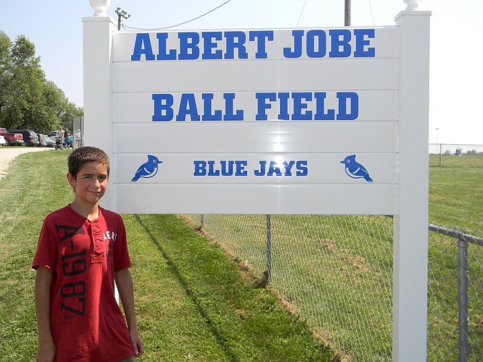 Current High Point student Luke Macias with a sign donated by Hoback Fence in honor of the Albert Jobe Ballfield dedication at the High Point Homecoming Saturday, Sept. 3.