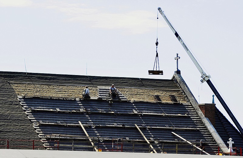 Workers install a new roof on the north side of the St. Peter Church on Wednesday afternoon. 