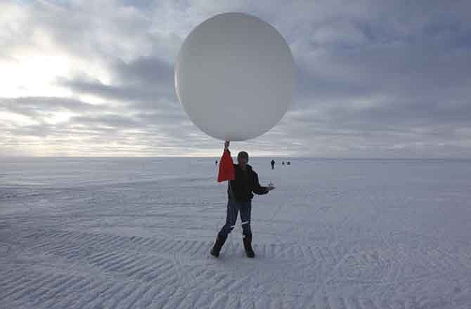 In this July 15, 2011 photo, atop roughly two miles of ice, technician Marie McLane launches a data-transmitting weather balloon at Summit Station, a remote research site operated by the U.S. National Science Foundation (NSF), and situated 10,500 feet above sea level, on top of the Greenland ice sheet. Climate scientists overwhelmingly agree that manmade greenhouse gases are warming the planet, accelerating the melt of Greenland's ice, and yet resistance to the idea appears to have hardened among many Americans. 