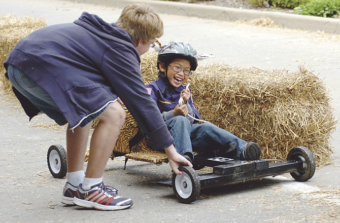 Ben Smith, 7, of Pack 333 at Lawson Elementary School, gets a little help after steering into a hay bale during his first Cub Mobile race Saturday morning on the West Main Street hill near the Secretary of State Information Center. Twenty scouts from Lawson took turns racing the pack's three cub mobiles.  
