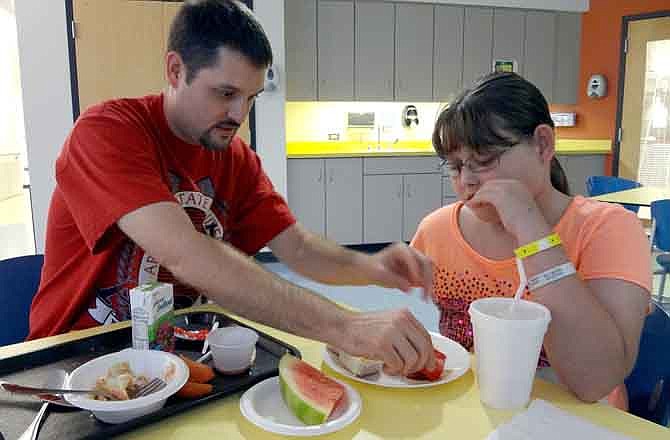 In a Sept. 9, 2011 photo, Matthew Rodery, left, helps his daughter Makenna, 10, squeeze ketchup for her fries at Ranken Jordan Pediatric Specialty Hospital in Maryland Heights. Makenna receives physical and occupational therapy at the hospital because her arm was amputated after a car accident in July. (St. Louis Post-Dispatch, Blythe Bernhard, via AP) 