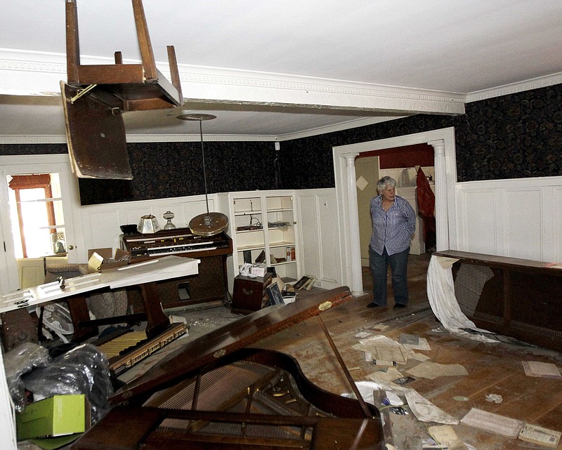 A piano chair hangs from the ceiling Monday in the home of Martha Gordon as she looks through her home destroyed during the flood in the aftermath of Hurricane Irene in Wayne, N.J. The chair, which was on top of a piano, was lodged into the ceiling when the Ramapo River crested, sending floodwater into the residence. Many residents waiting on aid are upset that politics is delaying their disaster help.