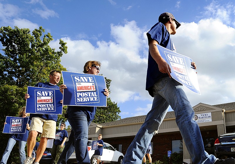 Local U.S. Postal Service workers rally Tuesday in front of U.S. Representative Vicky Hartzler's local office in support of federal legislation that would allow the post office to stop pre-funding retirement benefits.