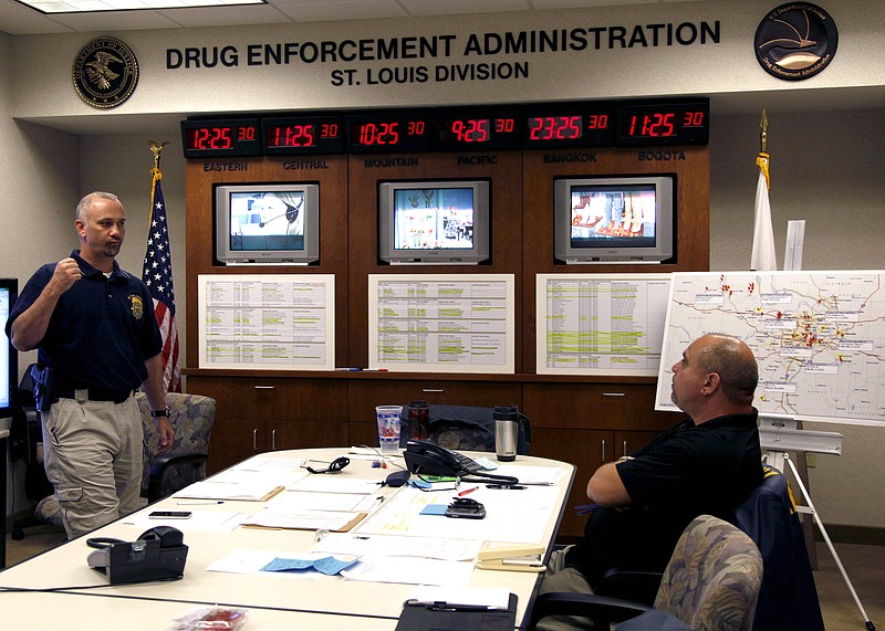 Special agent Jim Catalano, left, pumps his fist after hearing a suspected heroin trafficker has been located, while intelligence analyst Michael Shah, right, watches inside a command post at the Drug Enforcement Administration office Tuesday in St. Louis. 