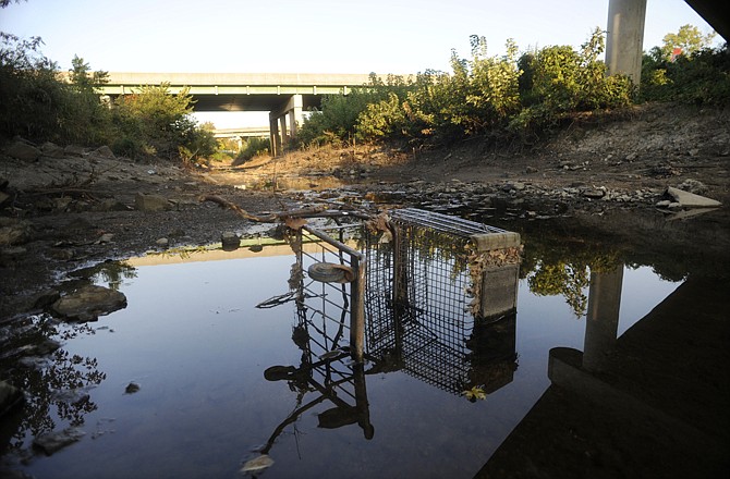 An abandoned grocery cart lies partially submerged under the U.S. 54 overpass in Wears Creek. The first Wears Creek clean up will be held Saturday.