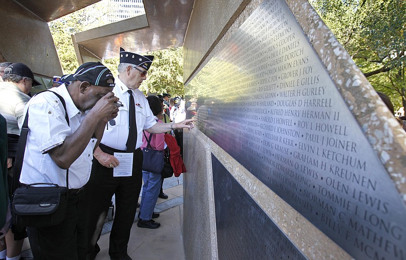 Following a dedication ceremony, the Rev. Phillip Layne, left,  photographs his brother's name as he and Bob Gadd walked through the Missouri Korean War Veterans Memorial for the first time on Wednesday in Washington Square Park in Kansas City, Mo.