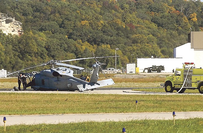 Jefferson City police officers stand by the cockpit of a Navy Seahawk helicopter as fire crews check the scene after the aircraft was damaged in an "aggressive emergency landing" Saturday at Memorial Airport. 