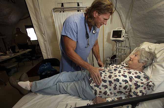 In this July 20, 2011 photo, emergency room physician David Hagedorn examines Shirley Ellsworth at a tent hospital housing St. Johns Regional Medical Center in Joplin, Mo. On May 22, 2011, one of America's worst tornadoes in half a century took dead aim at St. John's. The building would crumble around its staff and patients, but their hospital would continue. 