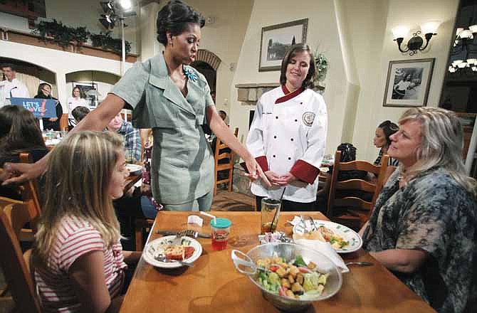 First Lady Michelle Obama, accompanied by Darden chef Julie Elkinton, second from right, talks to Charisse McElroy, right, and her daughter Jacqueline McElroy, 9, during a Let's Move! event in one of Darden's national restaurants in Hyattsville, Md., Thursday, Sept. 15, 2011. The first lady announced Darden Restaurants' commitment to reduce its calorie and sodium footprint and to provide greater choice and variety on its children's menus and make healthy options the default choice whenever possible.