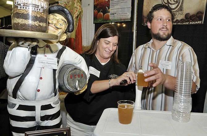 Not one to rest after winning, Deb Brown, owner of Prison Brews, serves up cold samples of home brew during the annual Chamber of Commerce Small Business Showcase at the Firley YMCA. Serving with her is employee Rod Dothage.