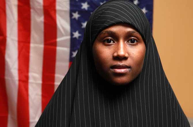 In this Thursday, Oct. 6, 2011 photo, Zainab Aweis, 20, a Somali Muslim poses in front of an American flag in Seattle, Wash. Rental car company Hertz indefinitely suspended 34 Somali Muslim shuttle drivers at Seattle-Tacoma International Airport for praying on company time, and the workers' union is trying to put them back in the driver's seat after what it calls a sudden policy change. (AP Photo/The Seattle Times, Ken Lambert)