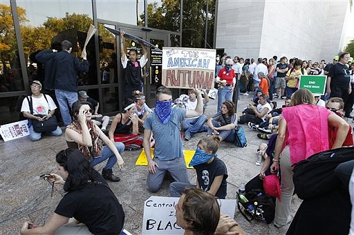 A group of demonstrators sit outside the entrance to the National Air and Space Museum in Washington after police pepper-sprayed a group of protestors trying to get into the museum Saturday, Oct. 8, 2011, as part of Occupy DC activities in Washington. One protester hold a sign with the writing "The American Autumn", a takeoff reference to the Arab Spring uprisings in the Middle East.