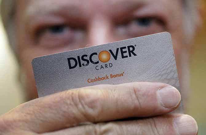 In this June 22, 2011 file photo, Steve Wheelock holds up his Discover Card in San Francisco. Once Discover was the only major card to offer cash back on purchases, but now other credit cards are luring valued cardholders with similar offers.