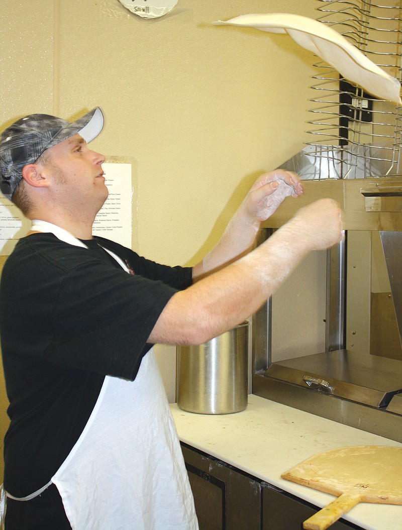 Justin Yancey, cook at Arris' Pizza, tosses pizza dough into the air Monday at the restaurant in Fulton.