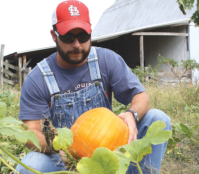 Landry Jones holds a pumpkin Monday at a farm east of Fulton that he grew for the Fulton Breakfast Optimist Club's fundraiser.