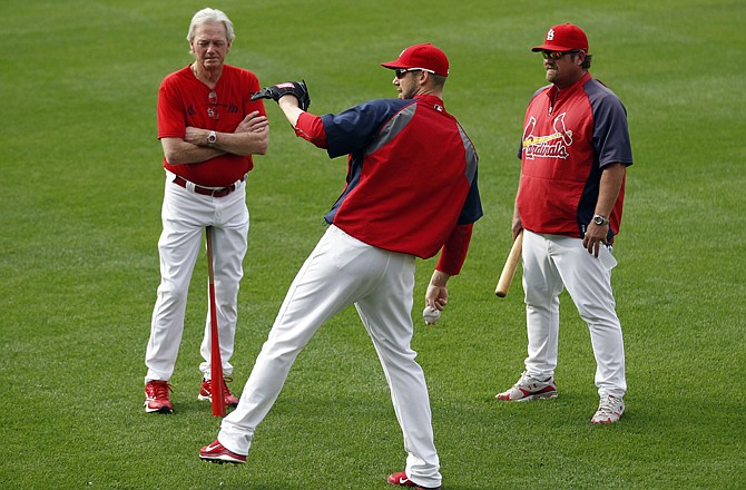 Chris Carpenter (center) of the Cardinals loosens up as St. Louis pitching coach Dave Duncan (left) and bullpen coach Derek Lilliquist look on during Tuesday's workout in St. Louis. Carpenter will get the start tonight against the Brewers in Game 3 of the NL championship series.