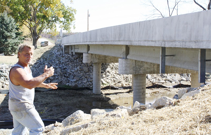 Sam Gaines, owner of Sam Gaines Construction Co. of New Bloomfield, Thursday explains the support system for a county bridge his firm built to federal specifications over Hillers Creek, about two miles east of New Bloomfield. The bridge on County Road 436 Thursday passed a final inspection by county and state officials.