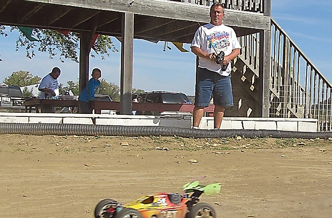George Carter, right, practices his radio-controlled car on the track in North Jefferson City on Sunday. Above him, Ryan Heislen races an unseen car on the track.
