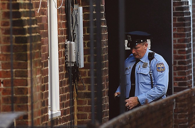 A police officer stands in an alley doorway of apartment building where four mentally disabled adults were found chained in the sub-basement.