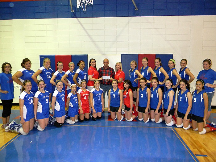 The California Middle School Seventh and Eight Grade Teams and Coaches Tiffany Brown, left, and Heather Henley, right, present a check to Jay Starr, center. The teams donated $200 and 41 jars of peanut butter to the Buddy Pack Program from a "Peanut Butter Jam" Fundraiser held Sept. 25 during their match with Blair Oaks.