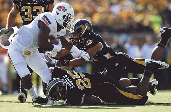 Oklahoma State running back Joseph Randle, left, runs for an 18-yard gain as Missouri's Matt White and Zaviar Gooden (25) defend during the first half of an NCAA college football game Saturday, Oct. 22, 2011, in Columbia, Mo.